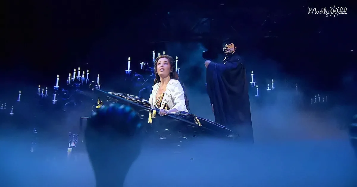 A woman in white and black attire sits on a carriage, while a man in a dark robe stands beside her, both under a dramatic...