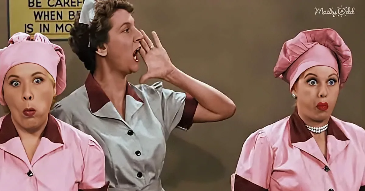 A man in a chef's uniform makes a surprised face, flanked by two women in pink uniforms, one with a pearl necklace.