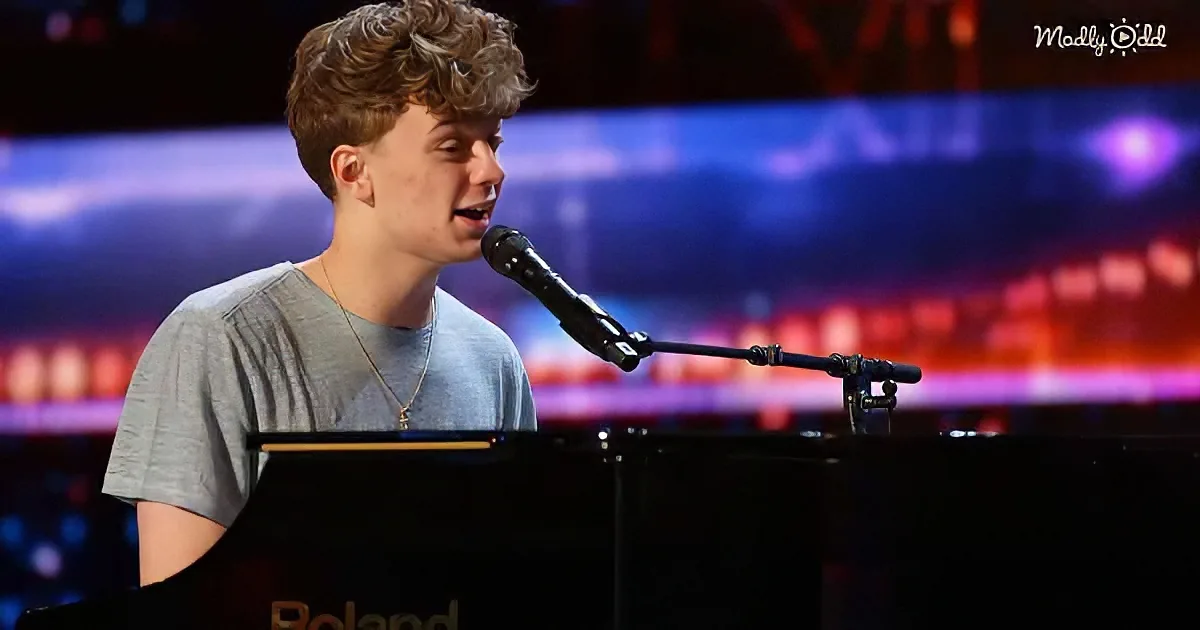 A young man sings into a microphone while playing a piano on a stage with colorful lights.