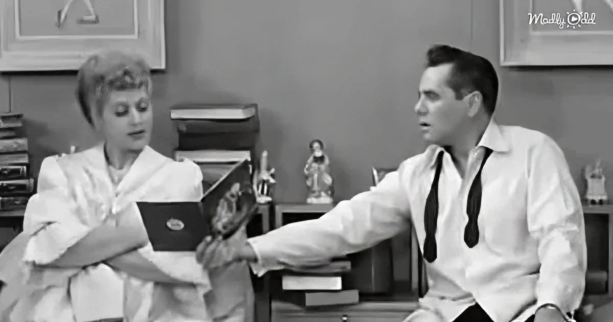 A man in a white shirt and tie gestures while holding a book, engaging in conversation with a woman in a white dress.