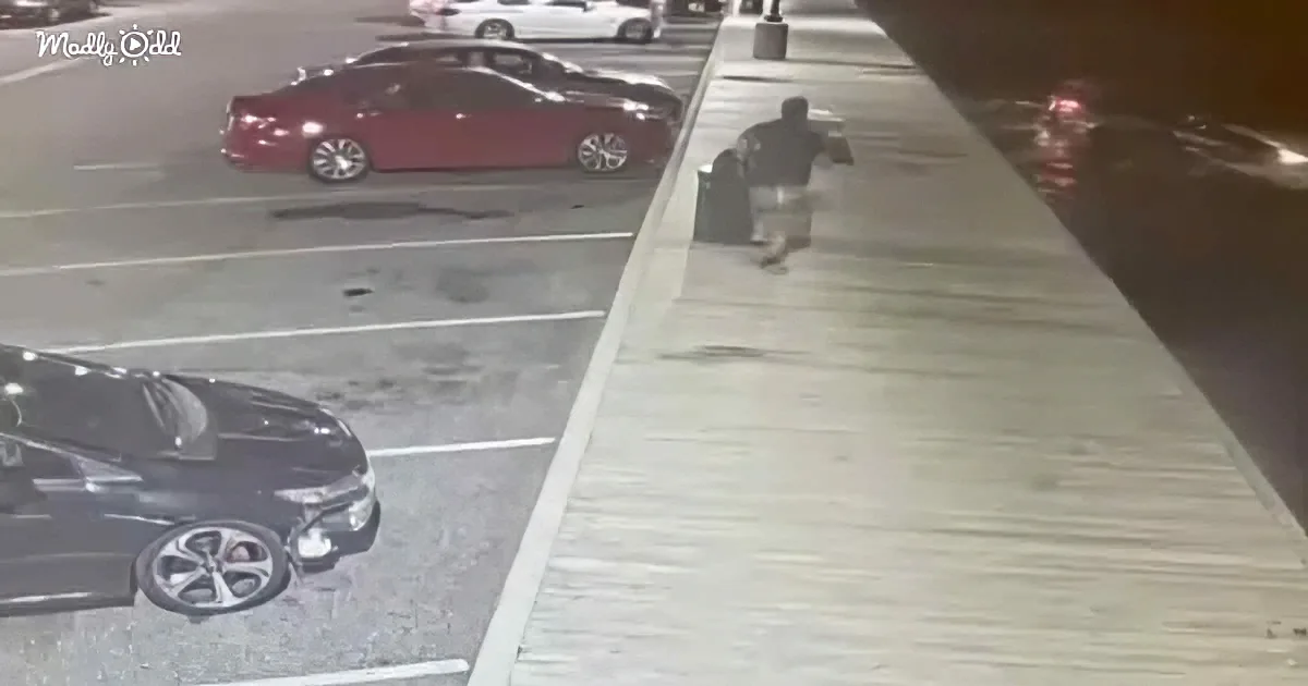 A person walks along a parking garage's edge, near parked cars.