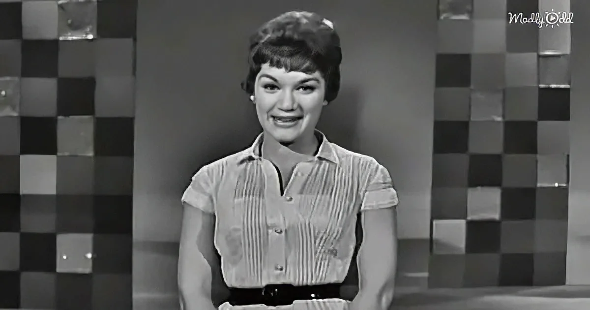 A woman in a striped shirt smiles against a checkered background.