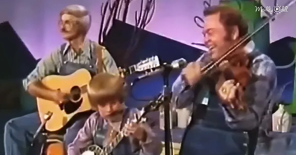 A man in a blue shirt plays a violin while another man in a plaid shirt strums a guitar.
