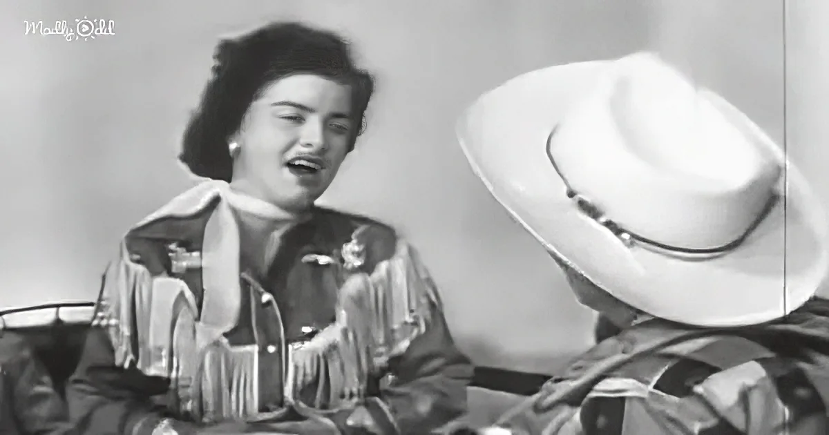 A woman in a Western-style outfit sings while a man in a cowboy hat listens.