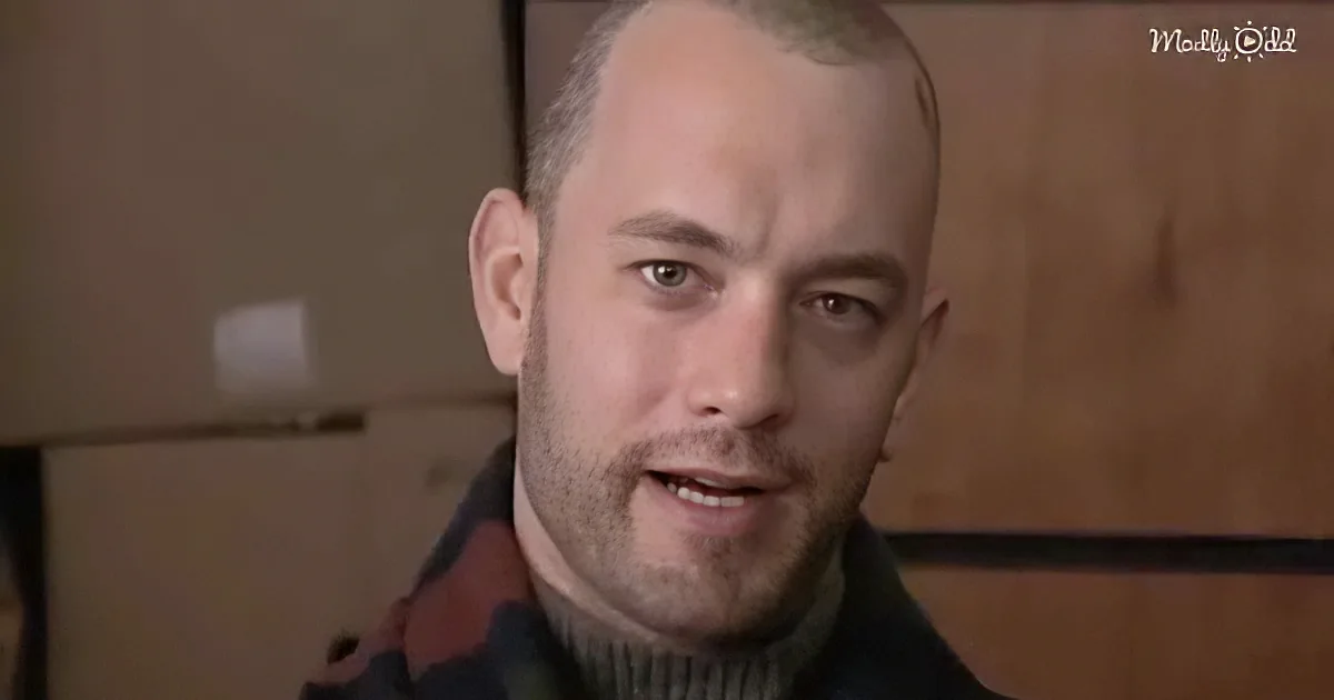 A man with a shaved head and a beard, wearing a dark jacket, looks directly at the camera with a serious expression.