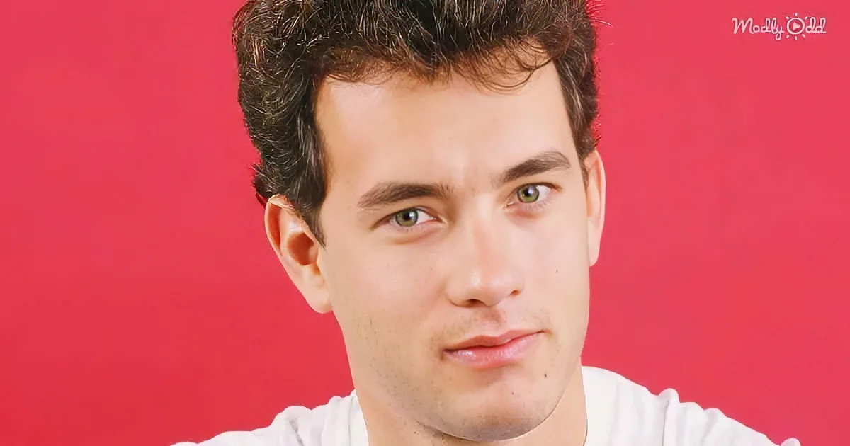 A person with short, dark hair and a white shirt against a red background.