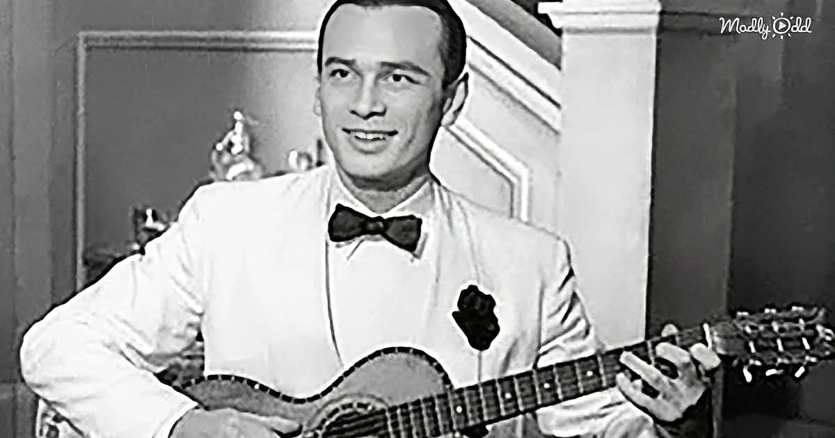 A man in a white shirt and bow tie plays a guitar, smiling.