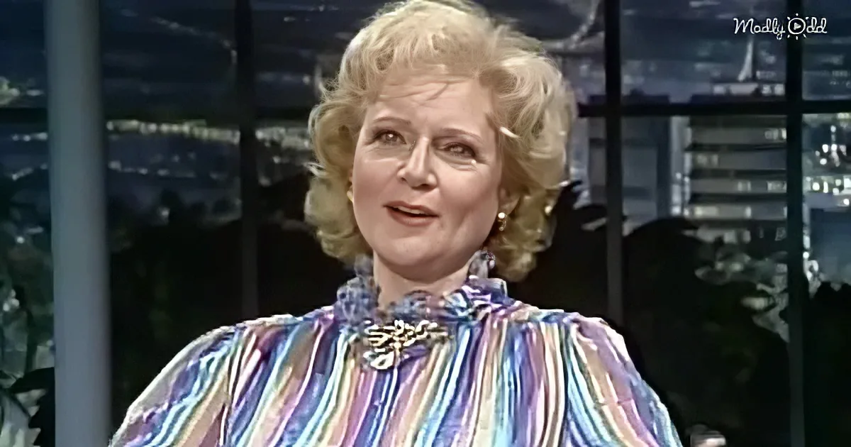 A woman with blonde hair in a colorful striped blouse is speaking on a talk show set.