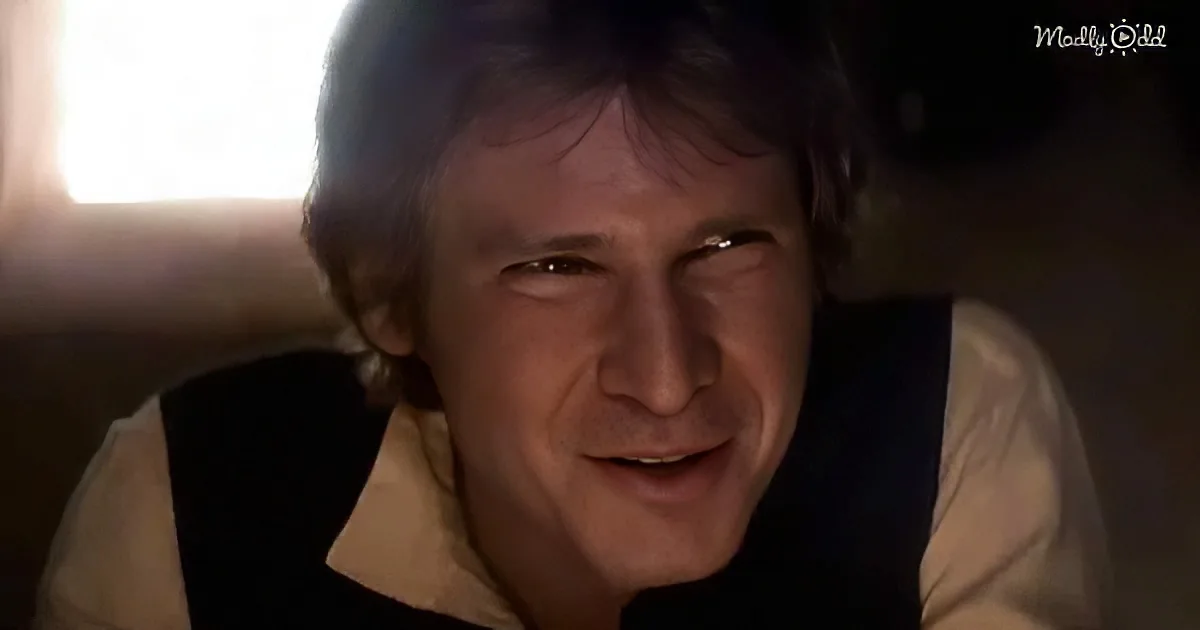 A man with short brown hair, wearing a white shirt and black vest, is smiling and looking to the side.