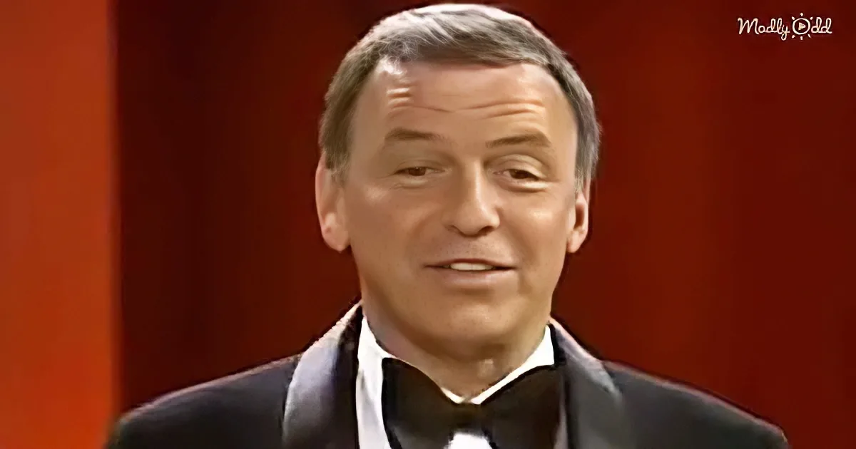 A man in a tuxedo with a bow tie and a red background.