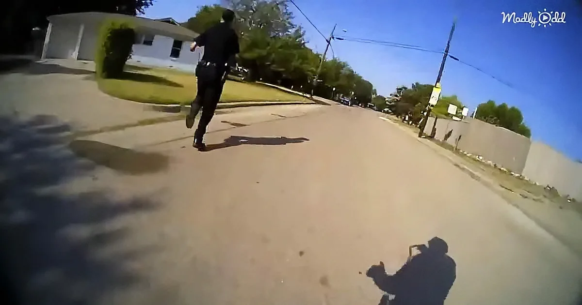 A police officer runs down a suburban street, with a person filming from the ground.