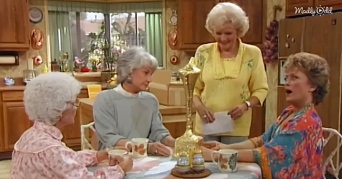 Betty White stands at a kitchen table with three other women, holding a piece of paper, while they all look at it.