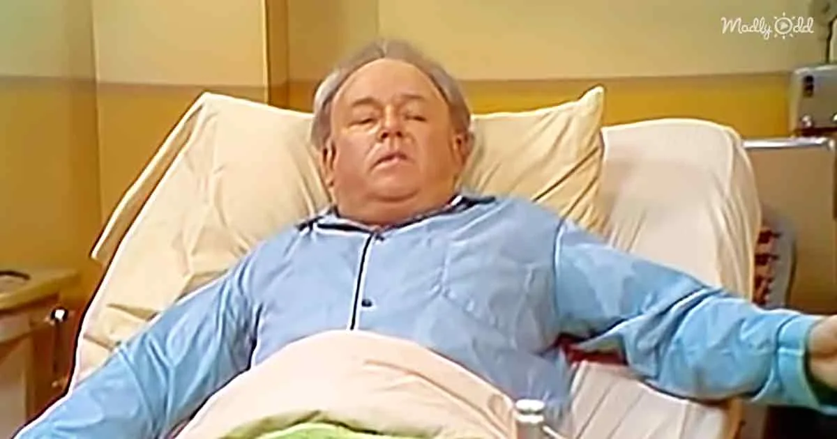 A man in a blue hospital gown lies in a bed, appearing relaxed or asleep.
