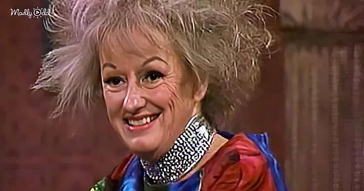 A smiling woman with wild, spiky hair, wearing a colorful outfit and a sparkly collar, appears in a vintage setting.