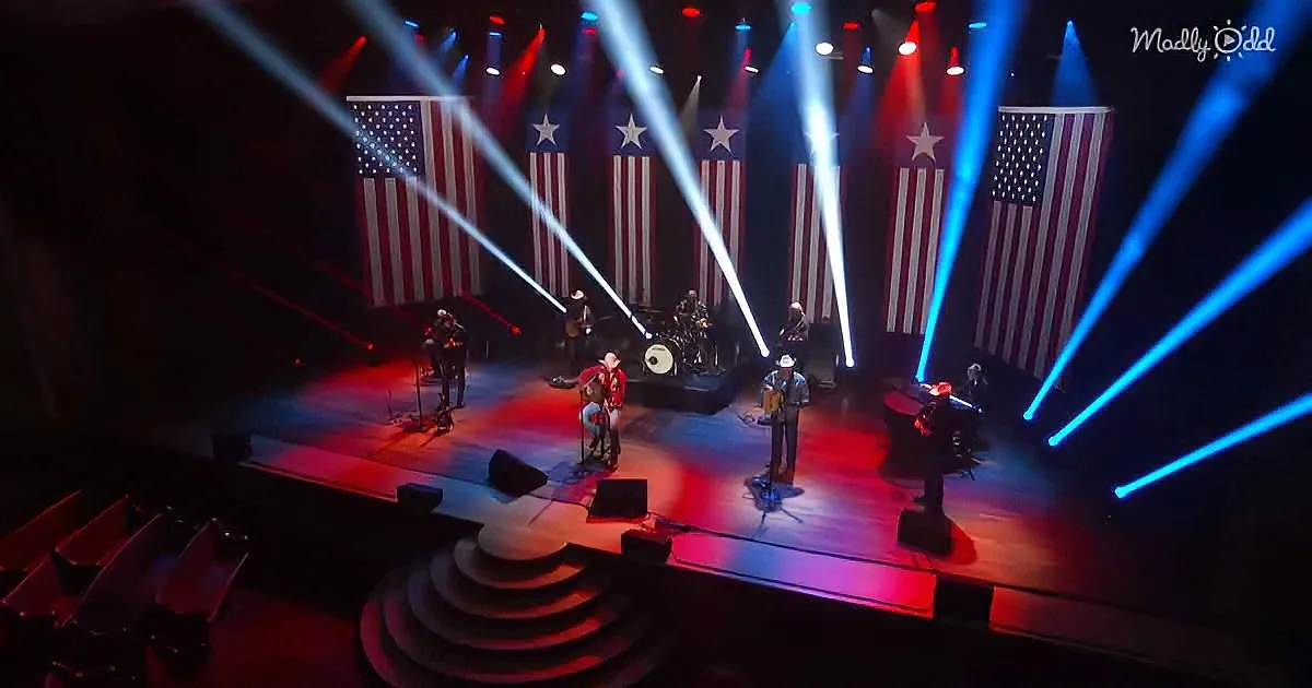 A band performs on stage with American flags and vibrant blue and red lighting.