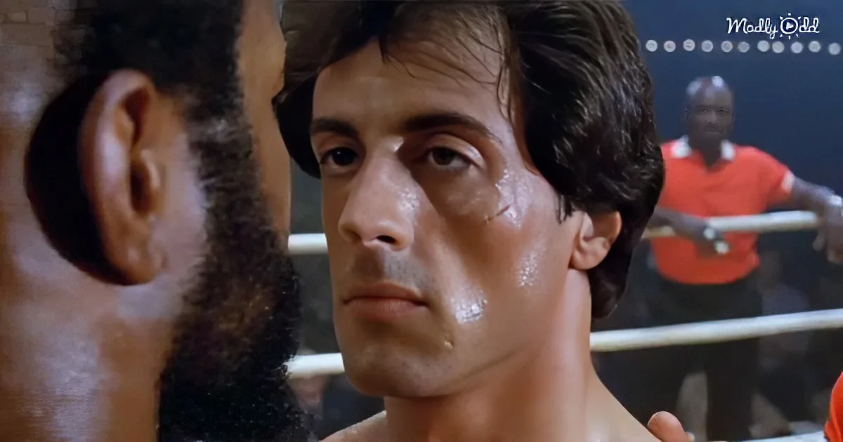 A man with a determined look, sweat on his face, in a boxing ring with another fighter.