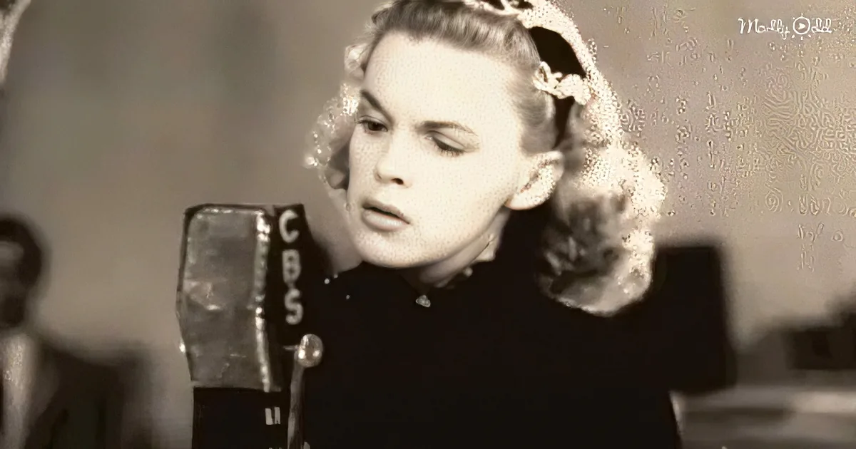 A woman with curly hair and a dark outfit is speaking into a CBS microphone.
