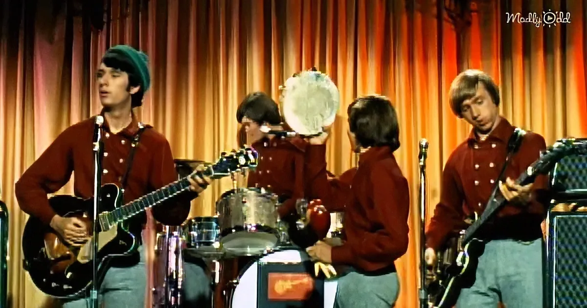 A band in red shirts and green hats performs on stage with a drum set and electric guitars.