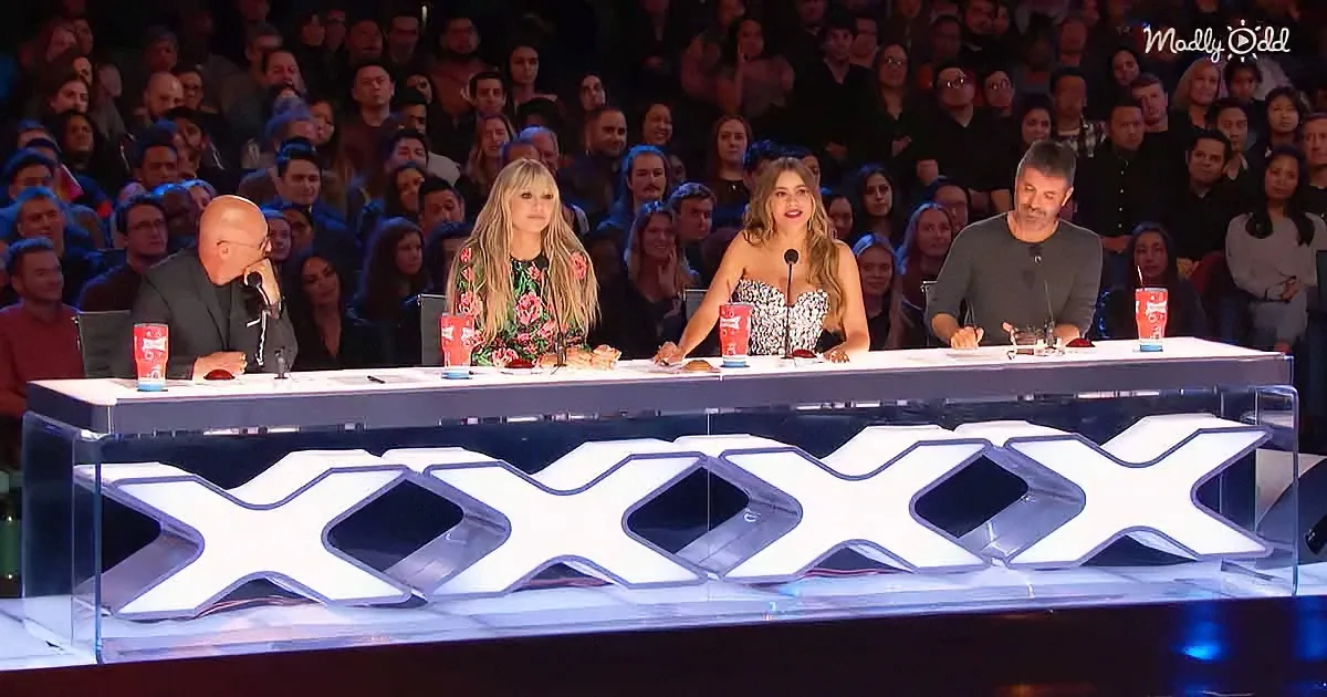 Judges sit at a table with "XXX" illuminated, surrounded by a cheering audience.