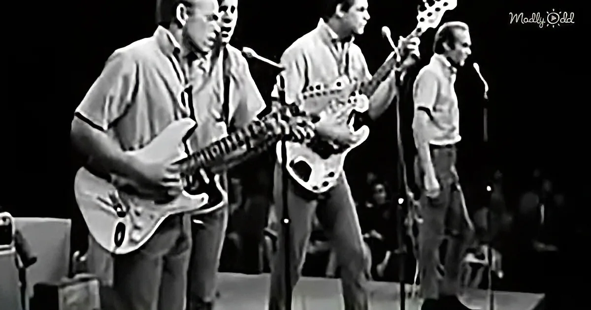 A band performs on stage, two guitarists play electric guitars, one sings into a microphone.