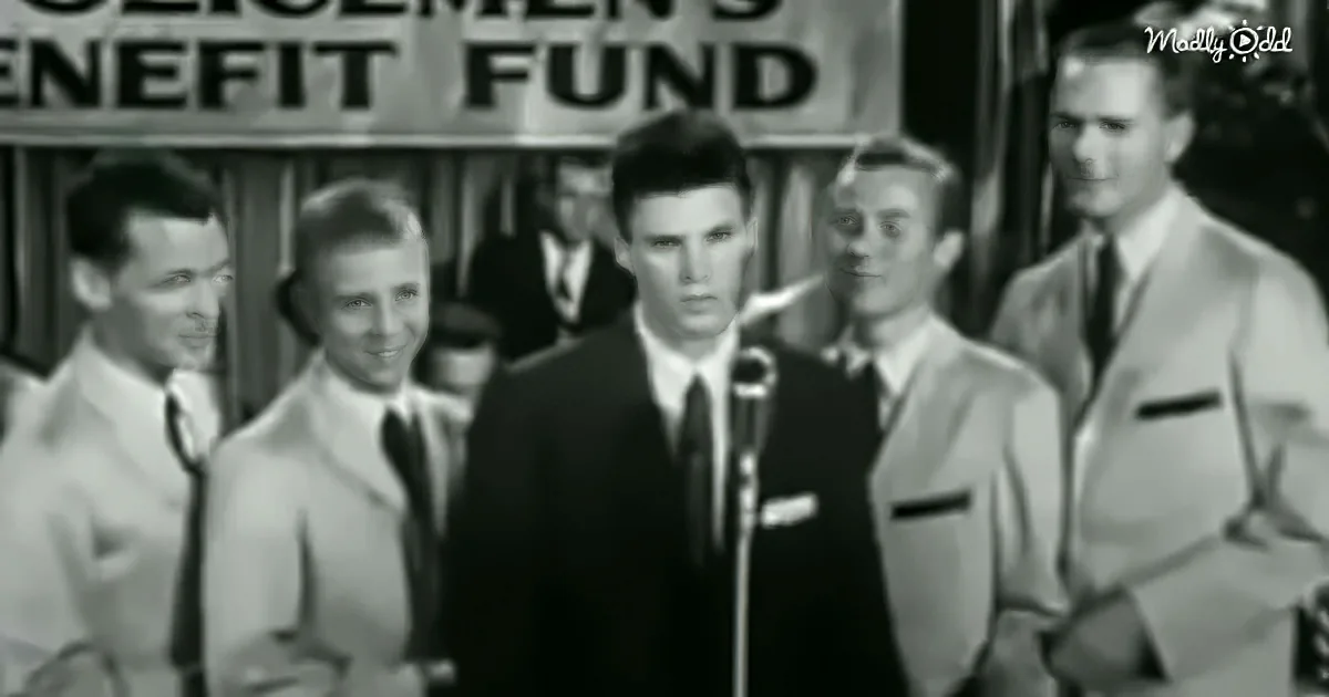 A man in a suit speaks into a microphone, surrounded by others in suits, with a banner reading "Citizens' Benefit Fund"...