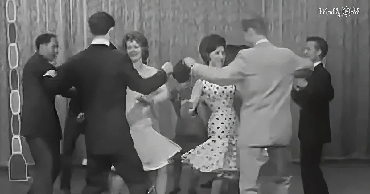 A group of people in formal attire is dancing in a circle, holding hands.