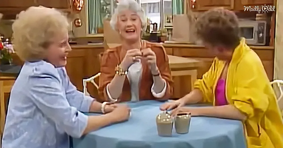 Three women sit at a table, one knitting, another smiling, and the third looking down, in a cozy kitchen setting.