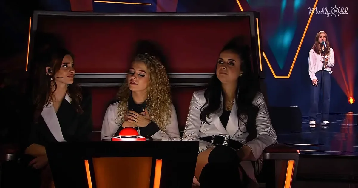 Three judges in white jackets sit at a table, one presses a red button, another looks up, a third listens.