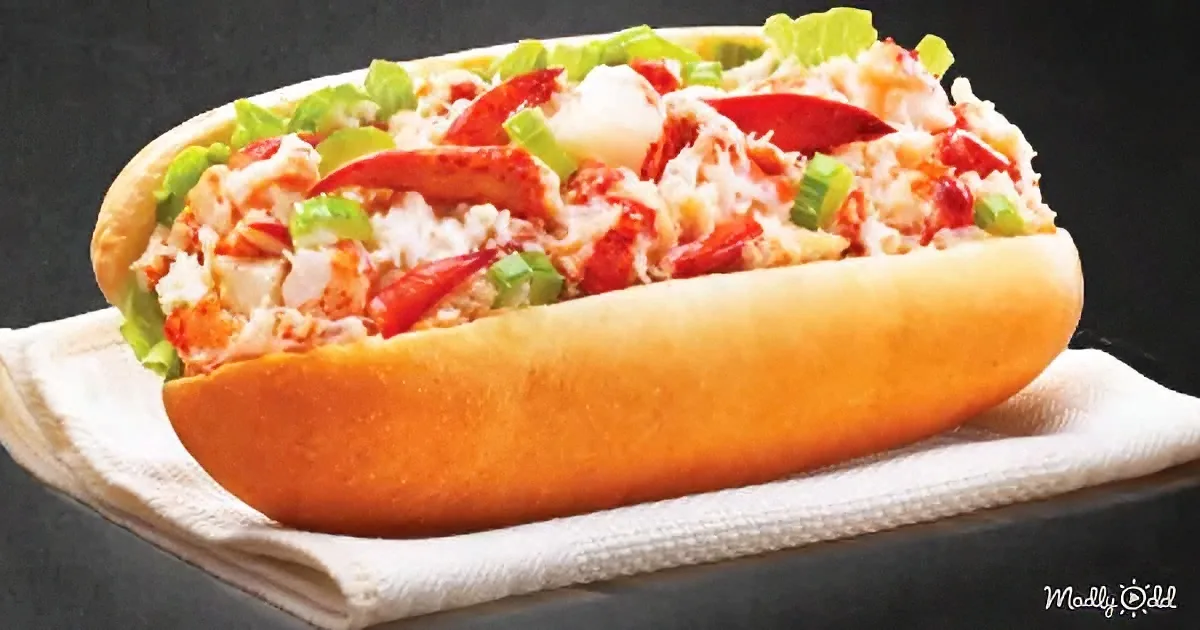 A lobster roll with lobster meat, lettuce, and green onions in a toasted bun.