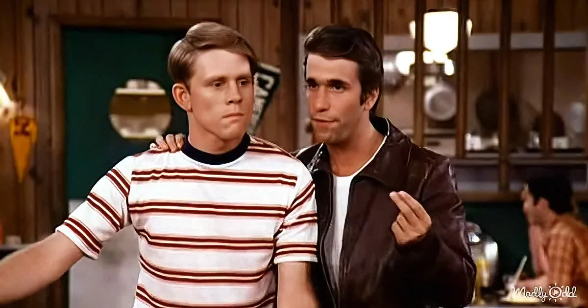 Two men, one in a striped shirt and the other in a leather jacket, stand together in a diner setting.