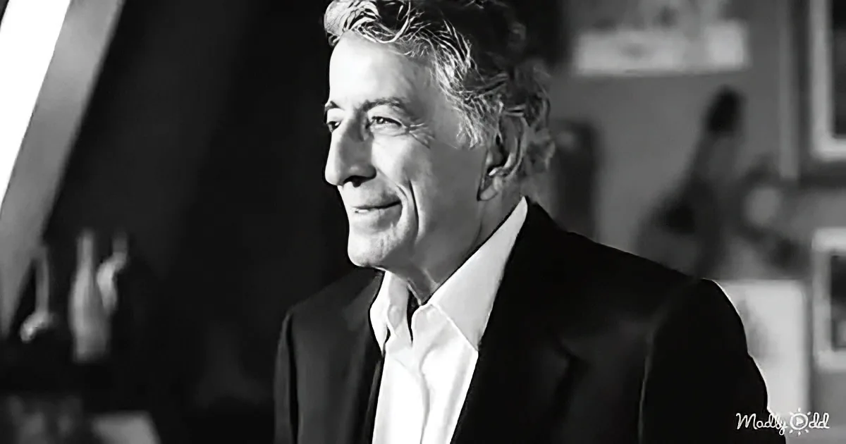 A man in a suit and white shirt, smiling, with curly hair, in a black-and-white photo.
