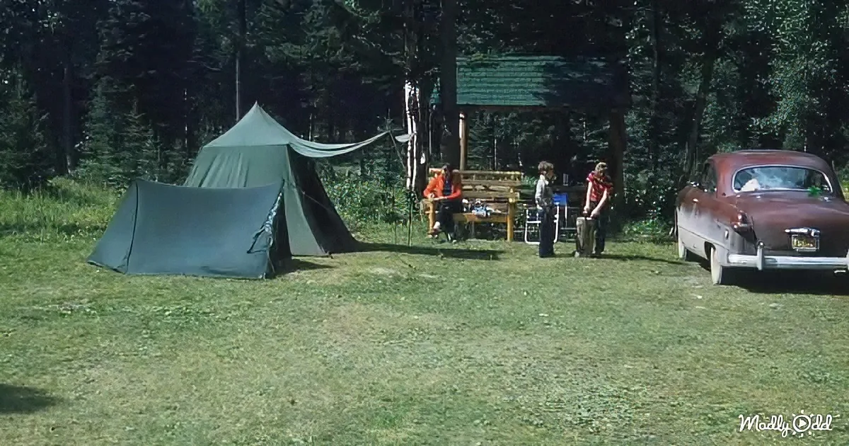 A vintage camping scene with a tent, people, a car, and a wooden structure in a forested area.