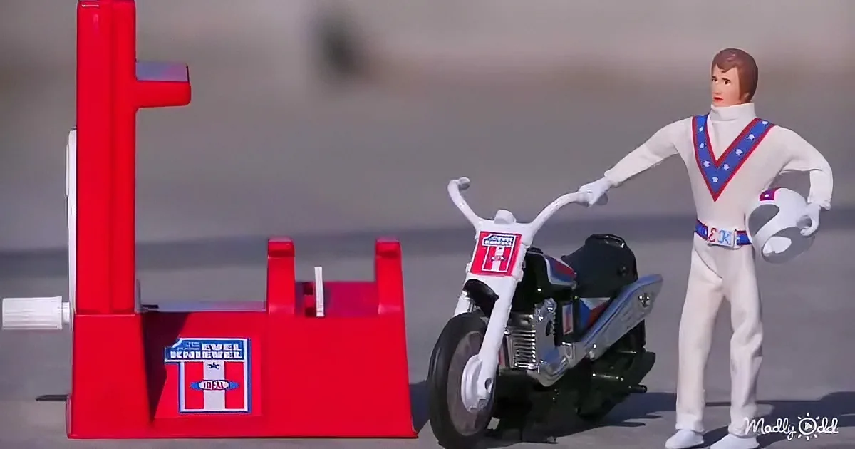 A toy Evel Knievel figure stands beside a motorcycle and ramp, ready for a stunt.