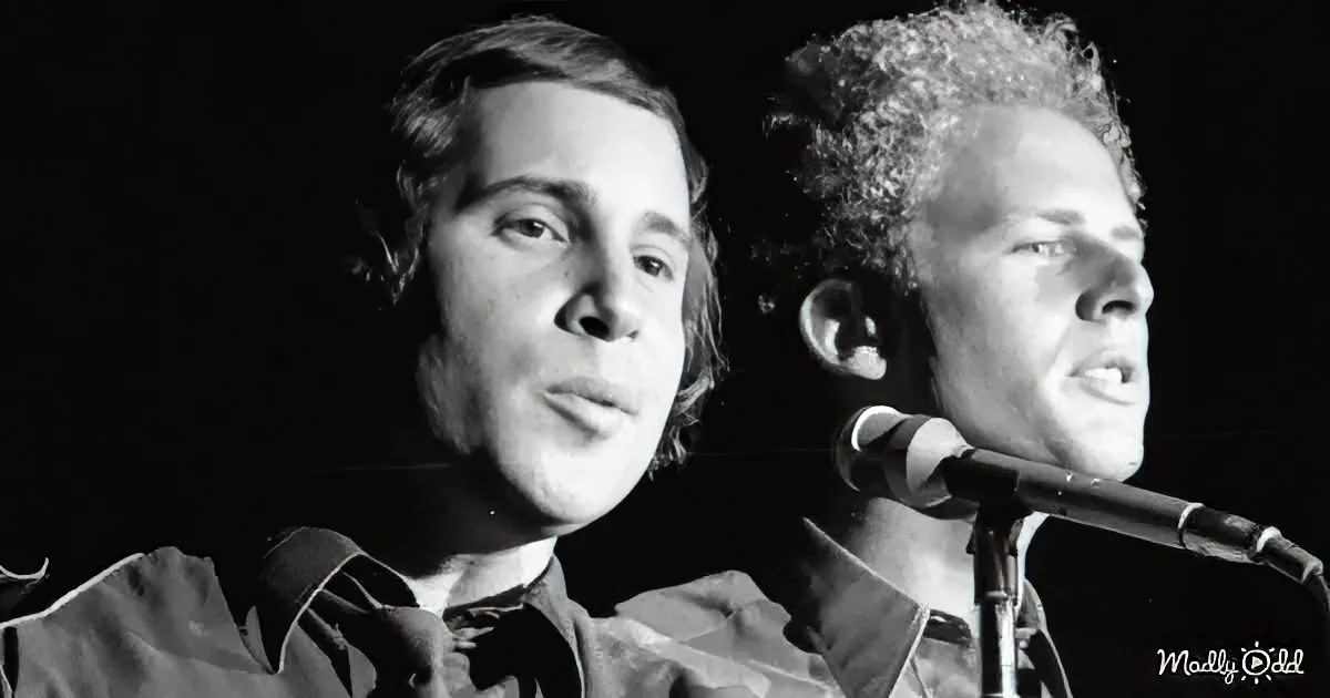 Two individuals, one singing into a microphone, both in casual attire, against a dark background.