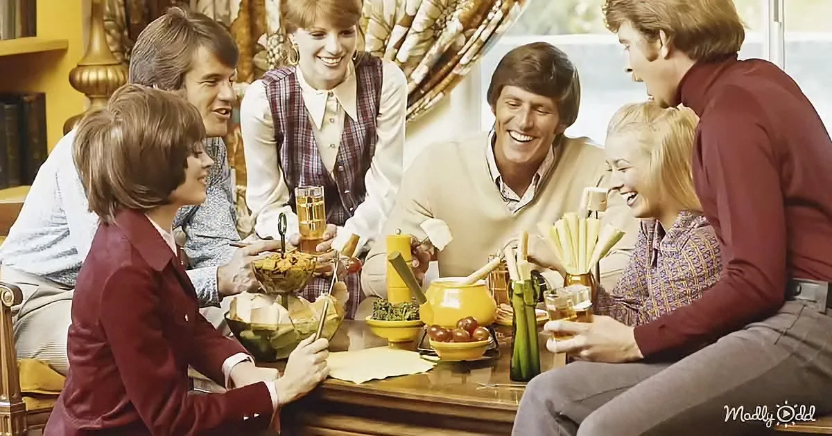 A group of people is gathered around a dining table, enjoying a meal and drinks, with a cheerful atmosphere.