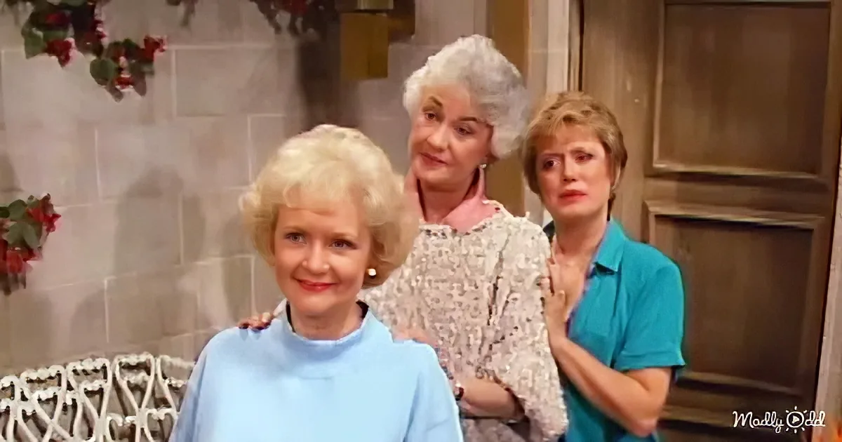 Three women, two standing behind one seated, in a cozy indoor setting with festive decorations.