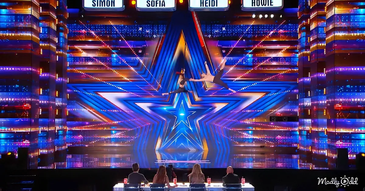 Two performers in mid-air against a star-shaped backdrop with judges' names above.