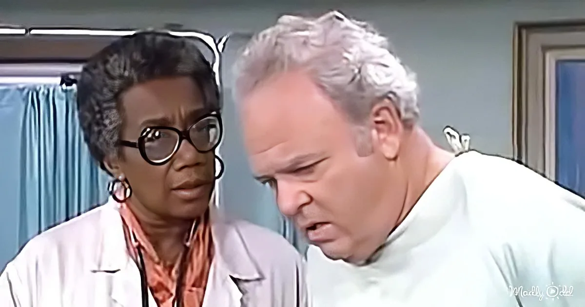 A woman in a white lab coat and glasses stands beside a man in a white shirt, both in a clinical setting.