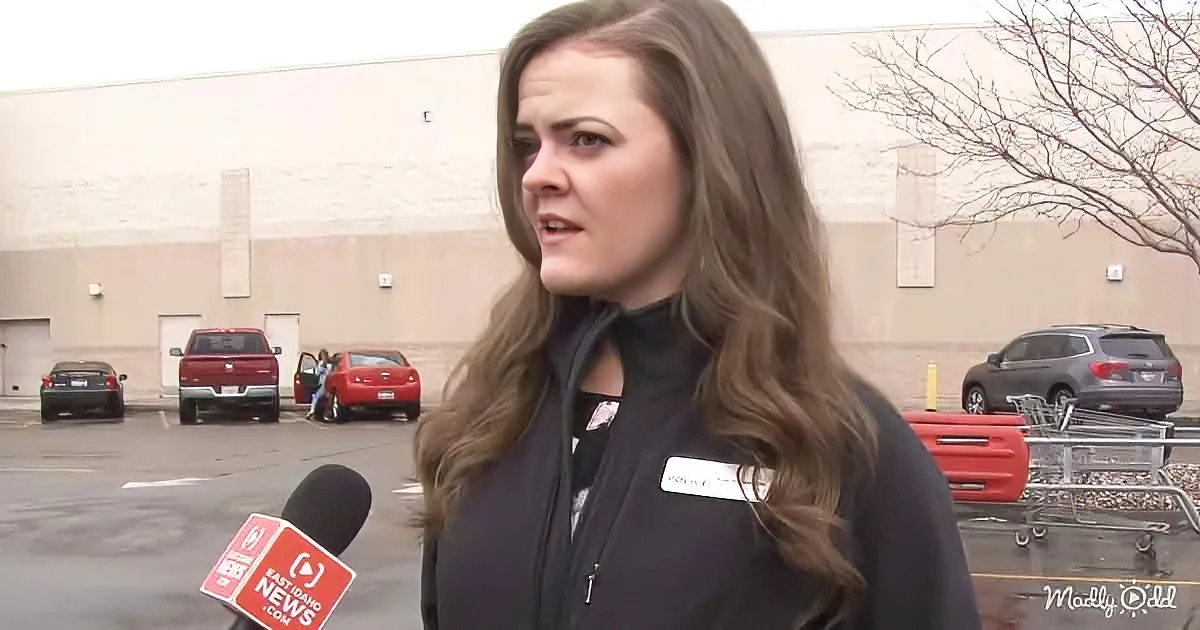 A woman in a black jacket speaks to a reporter in a parking lot with a Walmart in the background.