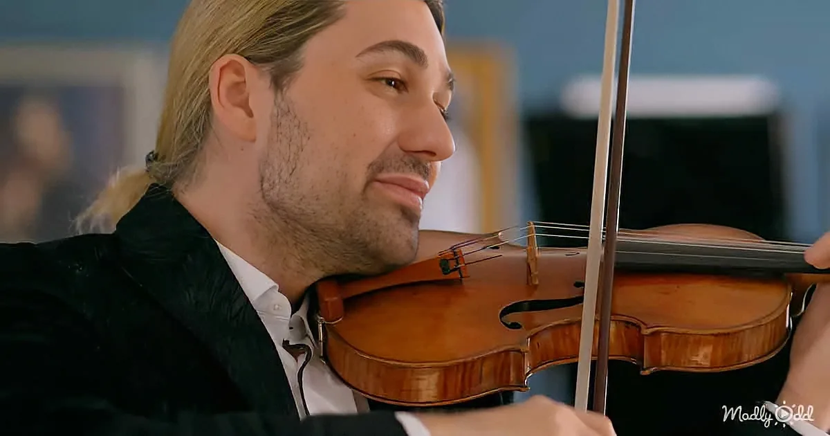 A man with long hair and a beard smiles while playing a violin.