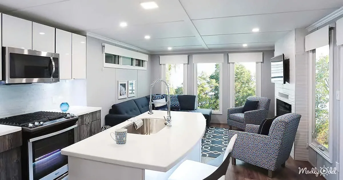 A modern kitchen with white cabinets, a black stove, and a central island with a sink and a blue mug.
