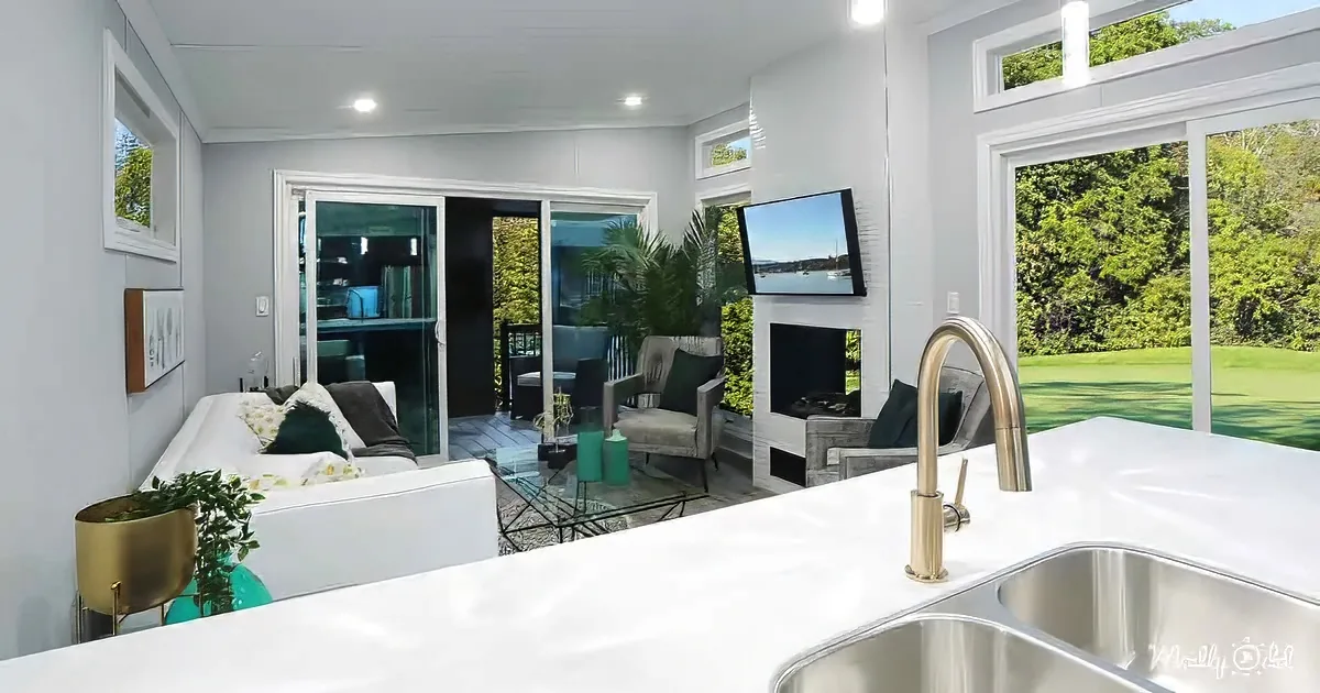 A modern kitchen with a white countertop, sink, and a view of a living area with a fireplace and sliding glass doors.