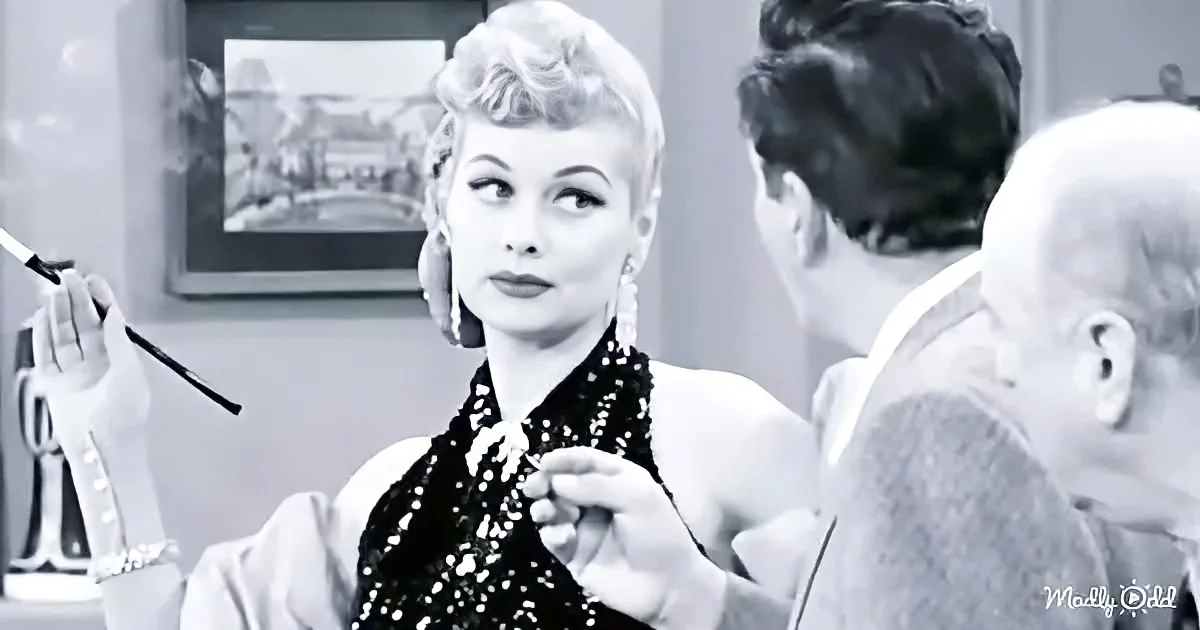 A woman in a glamorous outfit is being adjusted by someone, with another person in the background.