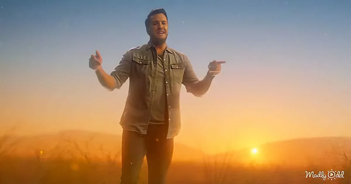 A man stands in a field at sunset, pointing to the sides with a serene backdrop.