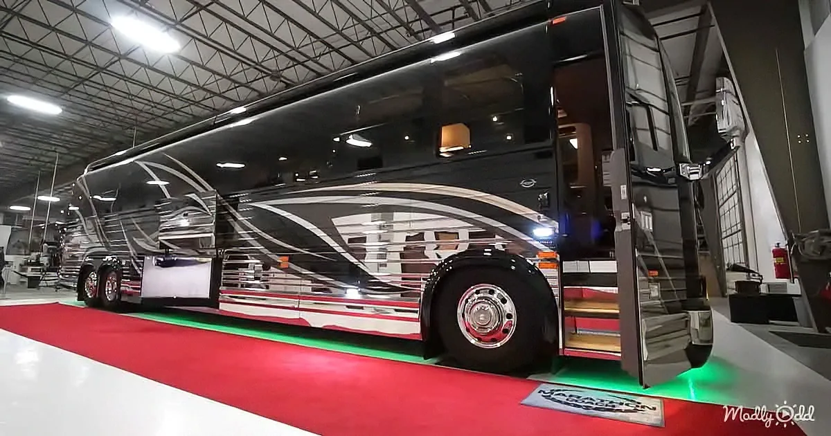 A luxurious black and white motorhome is displayed on a red carpet in a showroom.