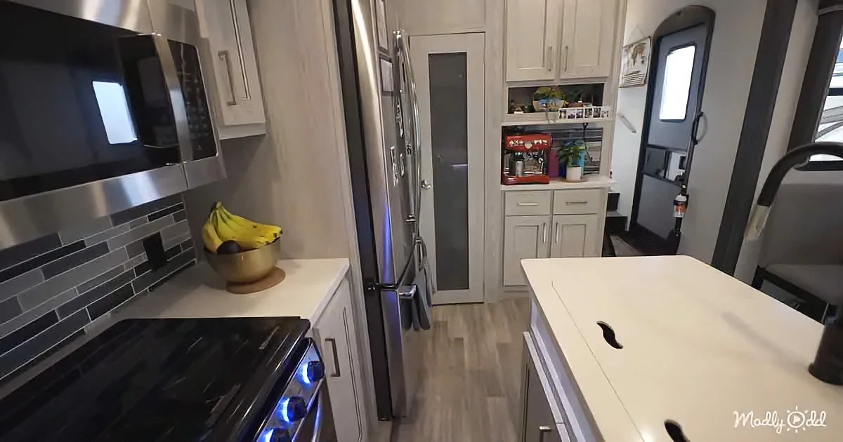 A modern kitchen with stainless steel appliances, white cabinets, and a bowl of bananas on the counter.