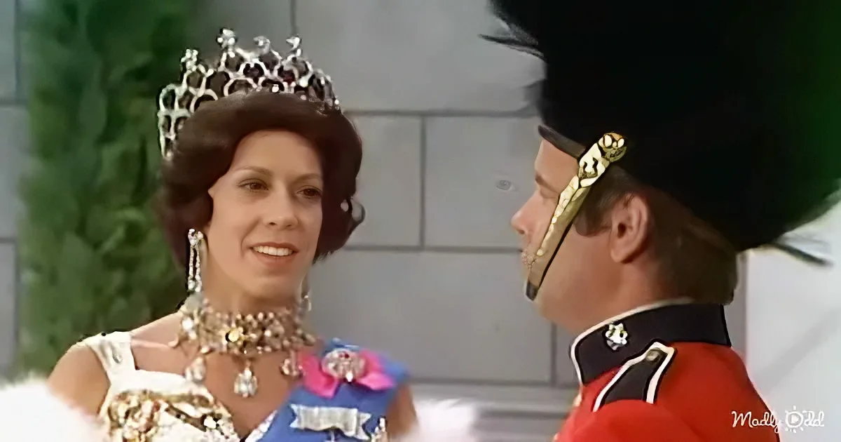 A woman in a crown and elaborate attire stands beside a man in a red military uniform with a gold sword.
