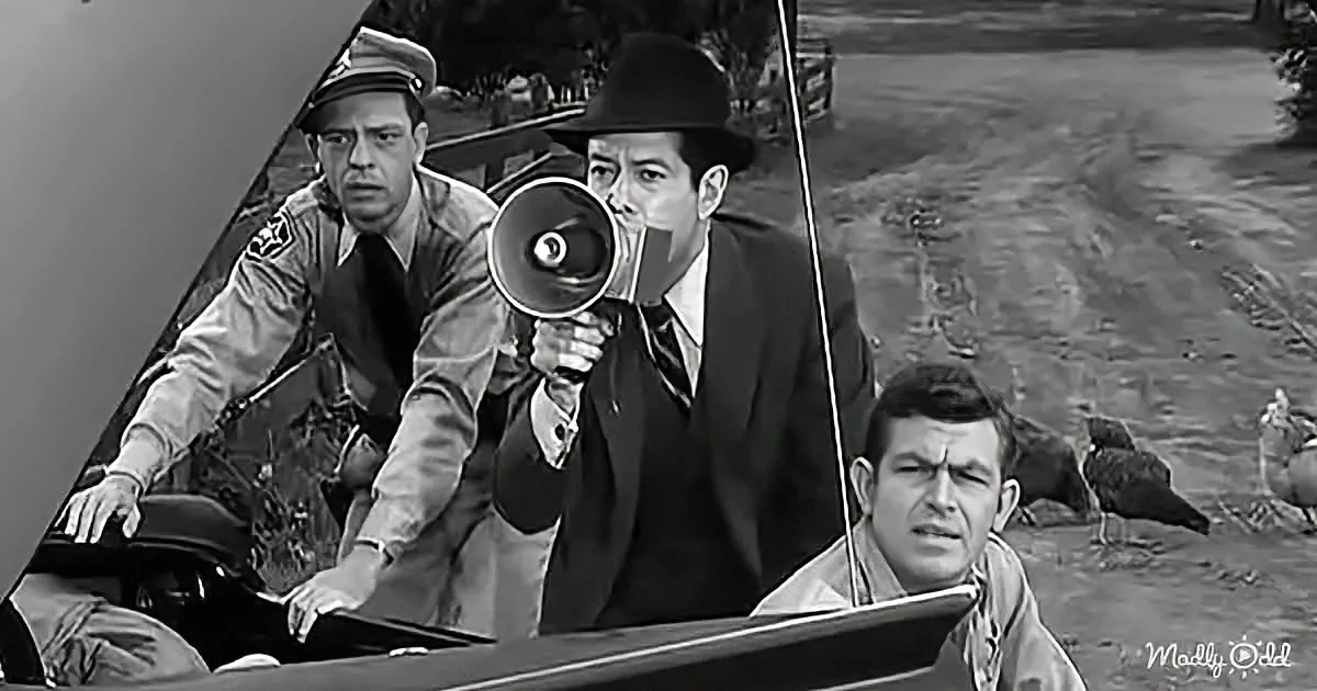 A man in a suit holds a megaphone while another in a uniform leans over a car, and a third man looks on in the background.