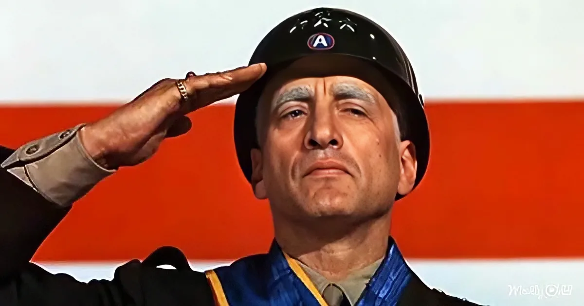 A man in military attire salutes, wearing a helmet with an "A" emblem, against a red and white background.