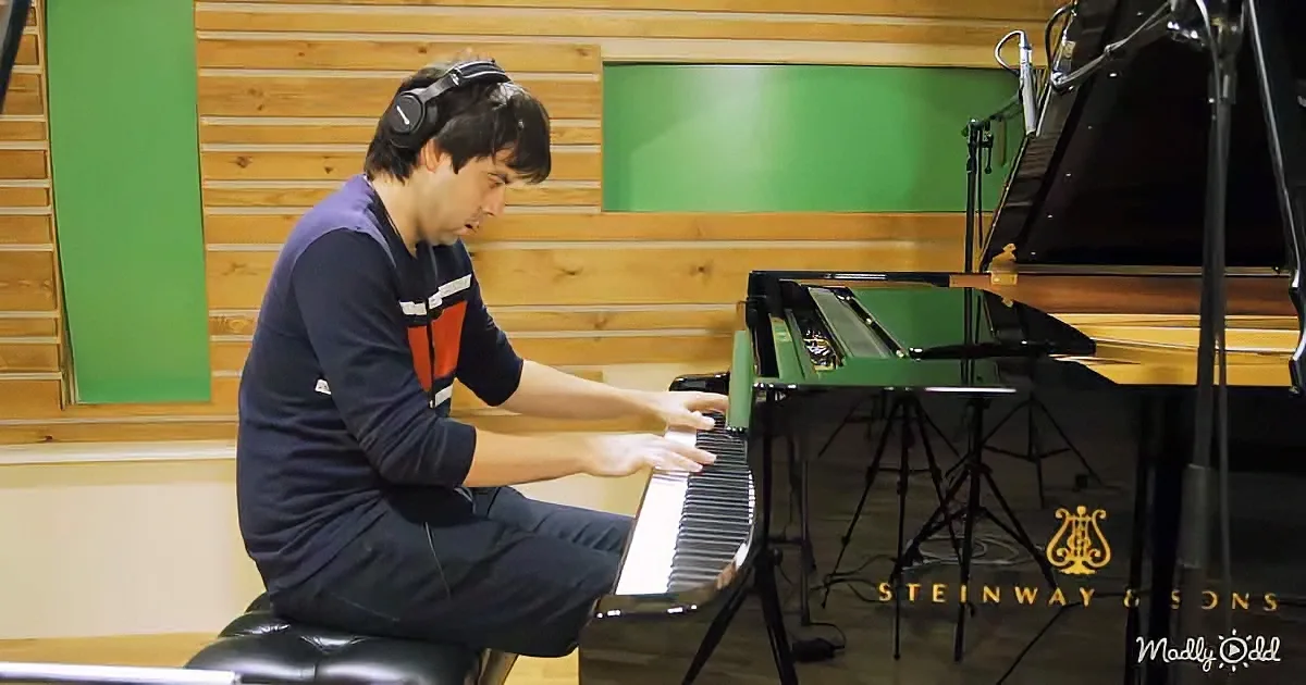 A person wearing headphones plays a Steinway & Sons piano in a studio with wood paneling and green accents.